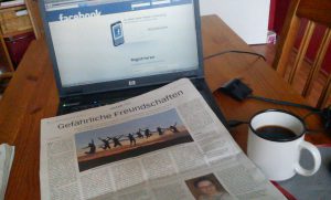 Laptop mit Zeitung und Kaffeetasse