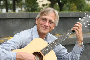 Christian Straube sitzt im Amphitheater und spielt Gitarre