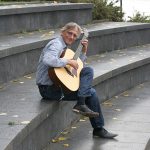 Christian Straube sitzt im Amphitheater und spielt Gitarre