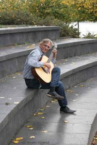 Christian Straube sitzt im Amphitheater und spielt Gitarre