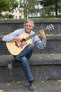 Christian Straube sitzt im Amphitheater und spielt Gitarre