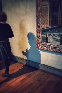 Frau geht von Bild in Museum weg, aber ihr Schatten sieht aus als ob er bleibt