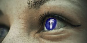 Augen in Nahaufnehme, in deren Iris das Facebooklogo leuchtet