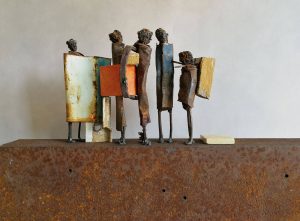Five differntly sized and coloured metal figures standing in line