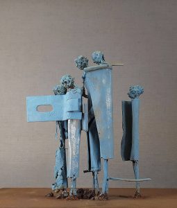 Five light blue coated metal figures one behind each other looking to the left.