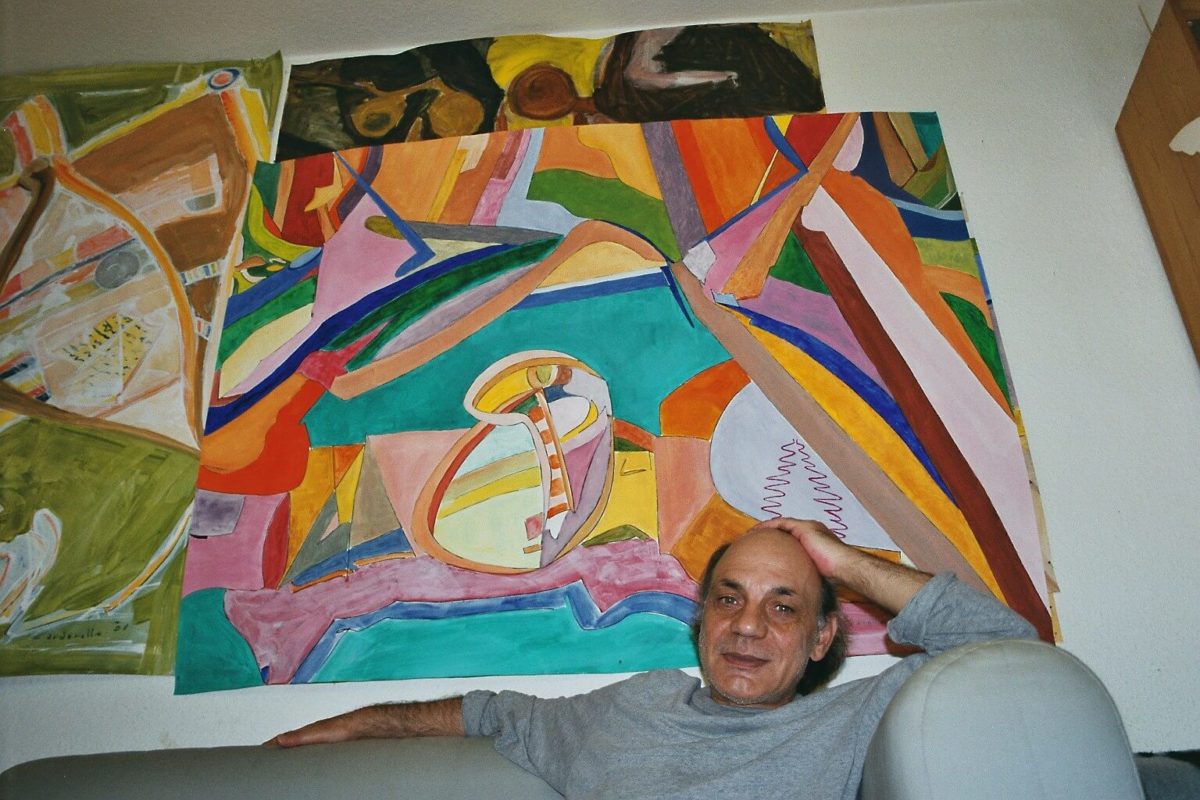 Renato zuahuse vor mehreren seiner Bilder