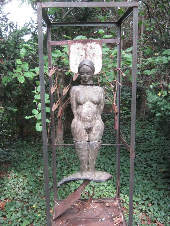 Frauenskulptur in Metallgerüst mit Garten im Hintergrund