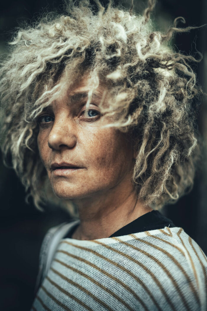 middle aged woman with short curly and blond colored hair and blue eyes