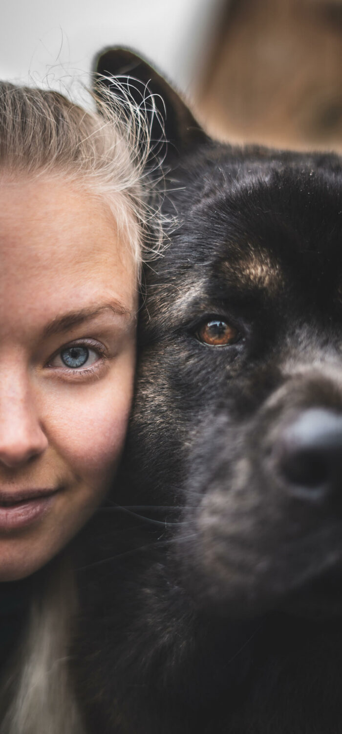 Half of a woman's face with blond hair and blue eyes next to half of a dog's face