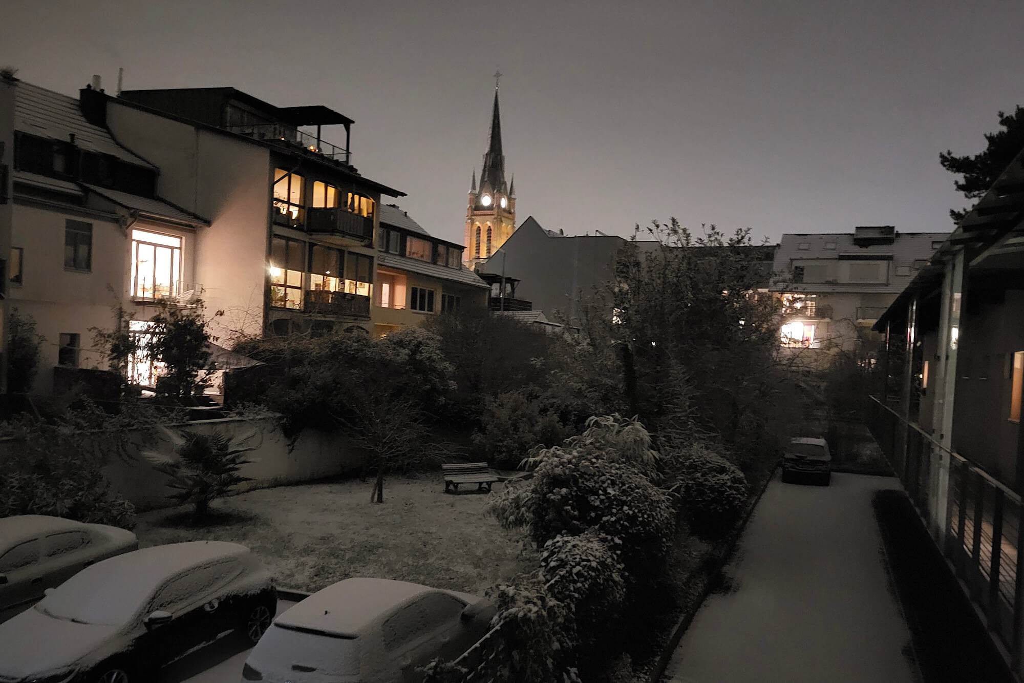 Nachtfoto von verschneiten Hinterhofgärten, in die aus den beleuchteten Häusern Licht fällt