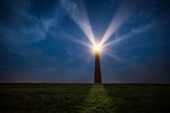 Das Licht eines Leuchtturms scheint durch die Nacht annder Küste