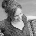 Sabria sitzt lächelnd auf einer Bank