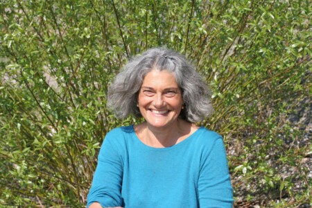 Christine pfauengleich vor einem Busch