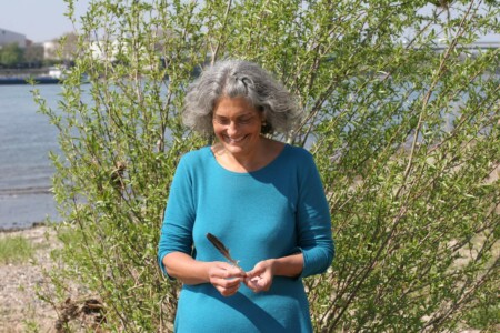 Christine spielt mit einer Feder am Rhein