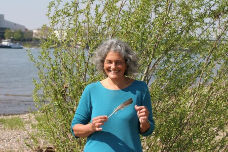 Christine spielt mit einer Feder am Rhein